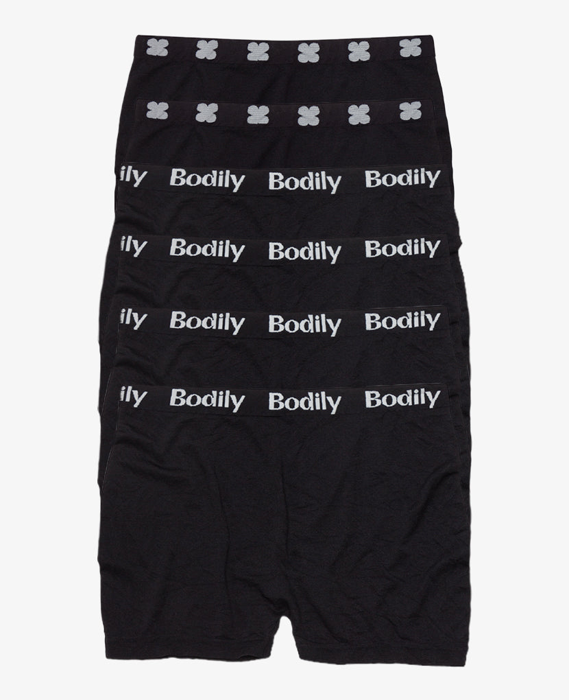 Six pairs of black mesh underwear are stacked in a row. Each waistband has “Bodily” in white text, while the top pair features a white floral pattern—ideal for postpartum bleeding or recovery after loss. Mesh Underwear: 6-Pack • Save 10%.