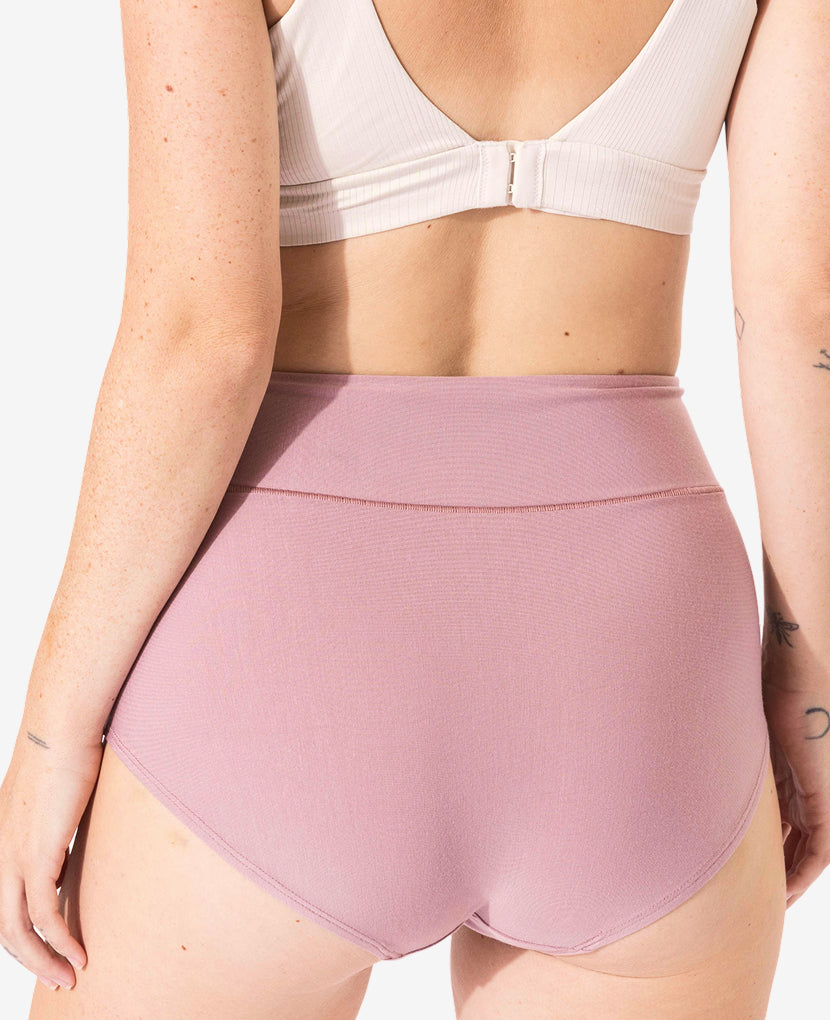 A person shown from the back, wearing The All-In Panty: 3-Pack • Save 16% in light pink high-waisted style and a beige bra, with visible arm tattoos, set against a plain white background.