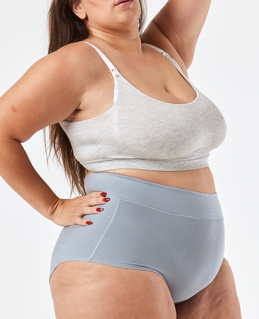 Woman wearing a gray sports bra and light blue high-waisted shorts on a white background in Clay/Dusk/Grey