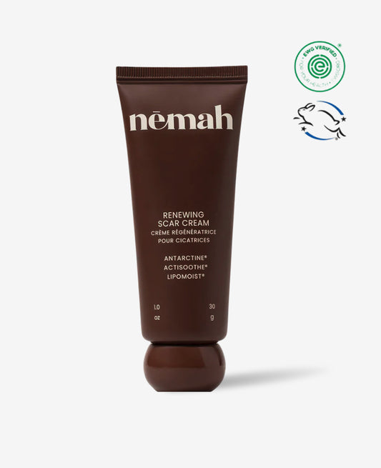 A brown tube of Renewing Scar Cream with white text is shown upright on a white background, featuring dermatologist-tested, eco-friendly, and cruelty-free certification symbols to the right.
