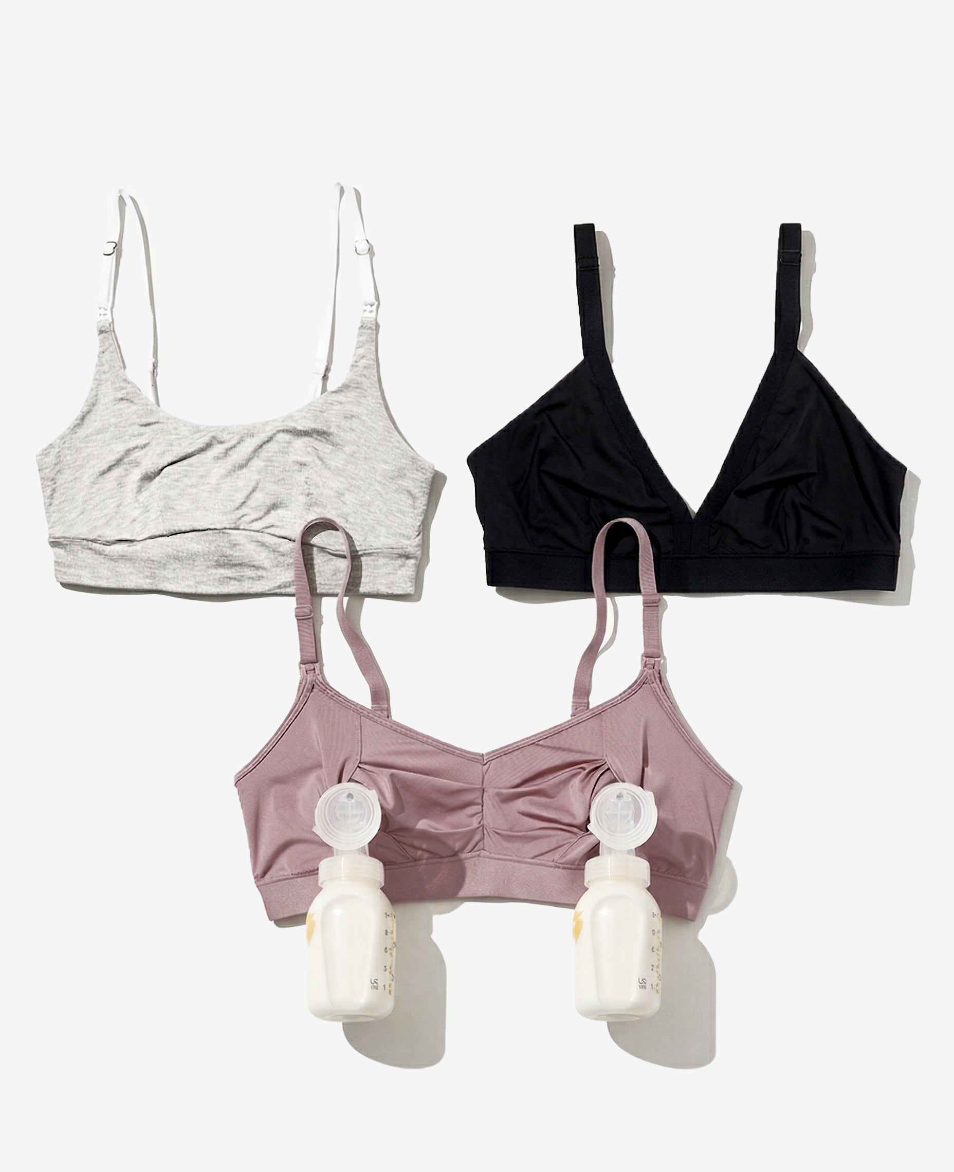 The Stages of Breastfeeding Bundle includes three nursing bras in gray, black, and mauve on a white background. The mauve bra features two attached breast pump bottles.