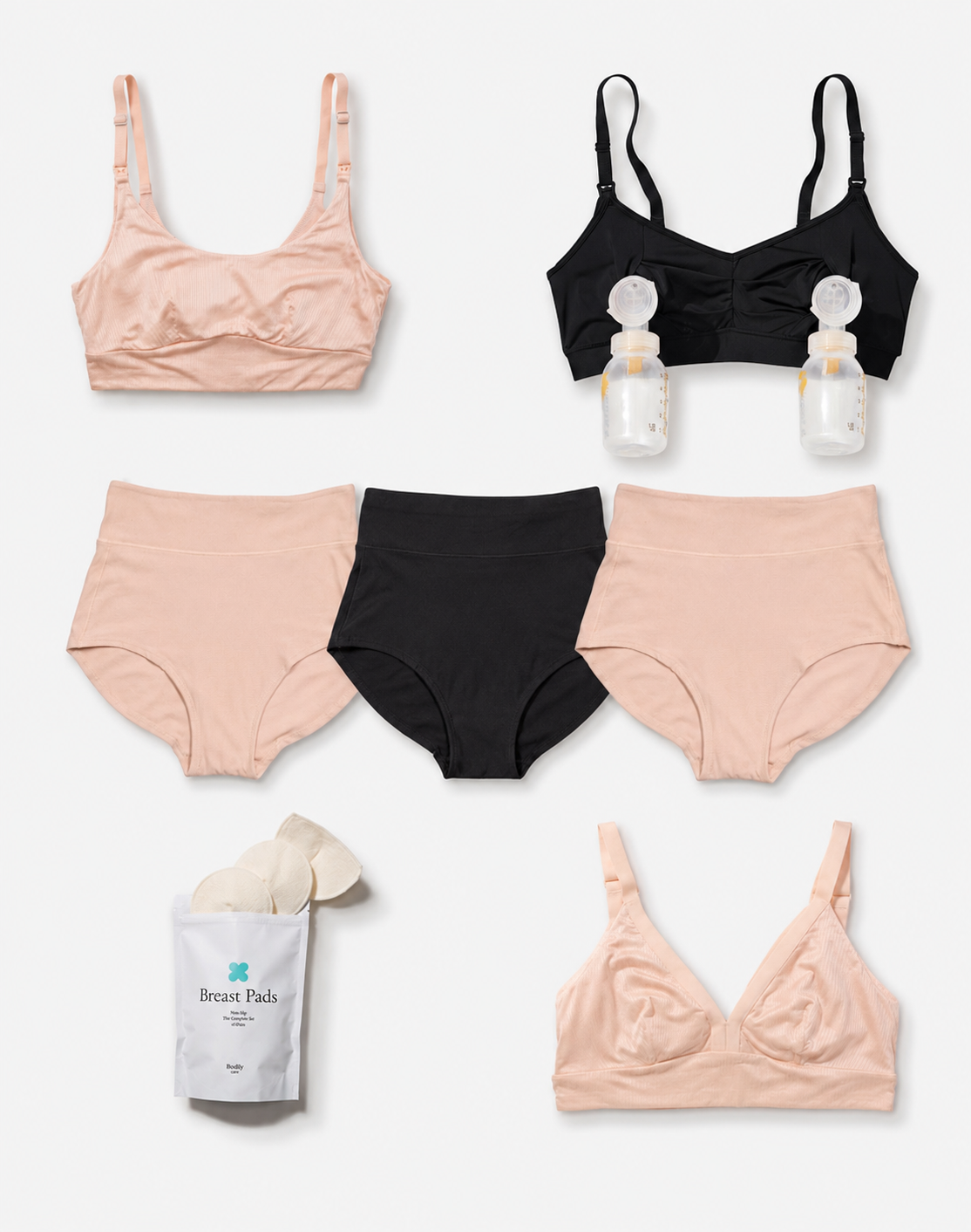 A flat lay of maternity and nursing underwear in three colors: light peach, black, and white. The set includes two light peach bras, two black high-waisted briefs, a white package of breast pads, and two clear nursing bottles with white caps.